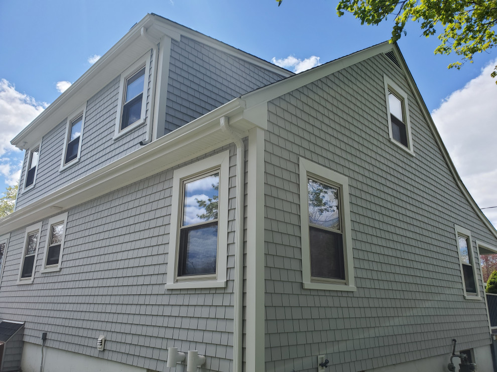 Photo of a two-storey grey house exterior in Providence with vinyl siding and shingle siding.