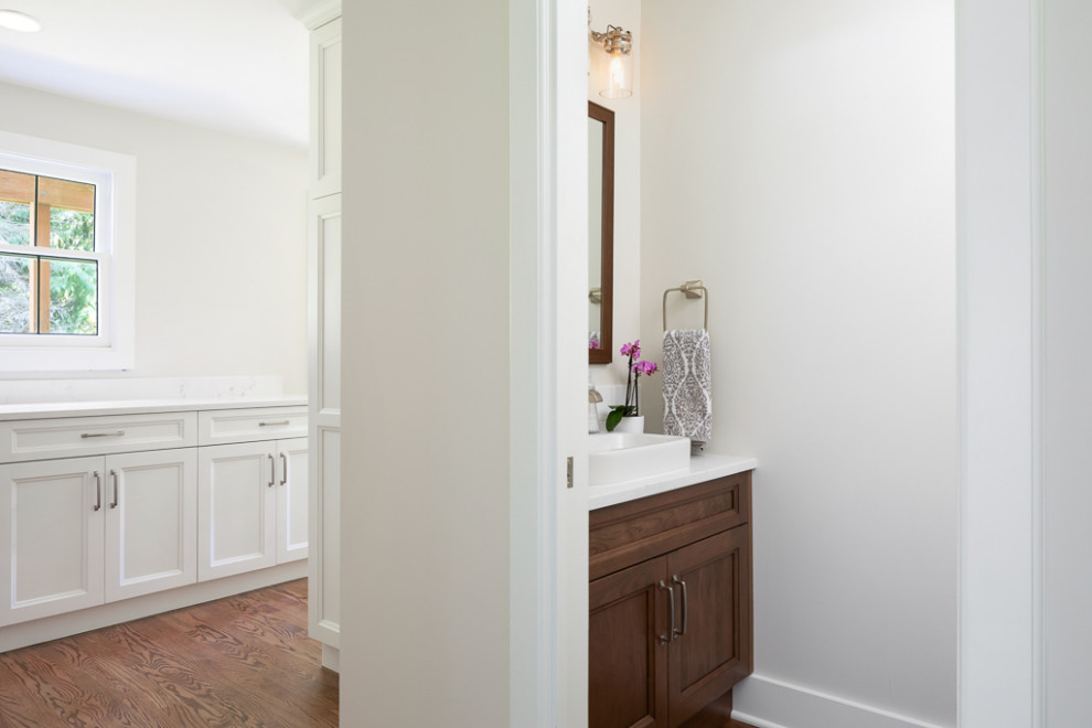 This is an example of a small transitional powder room in Seattle with recessed-panel cabinets, dark wood cabinets, a two-piece toilet, ceramic tile, grey walls, dark hardwood floors, a vessel sink, engineered quartz benchtops, brown floor, white benchtops and a built-in vanity.