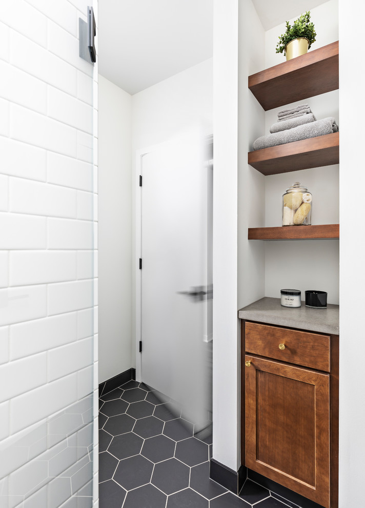 Mid-sized eclectic 3/4 bathroom in Detroit with recessed-panel cabinets, medium wood cabinets, an alcove shower, a two-piece toilet, white tile, subway tile, white walls, ceramic floors, a vessel sink, black floor, a hinged shower door, grey benchtops and concrete benchtops.