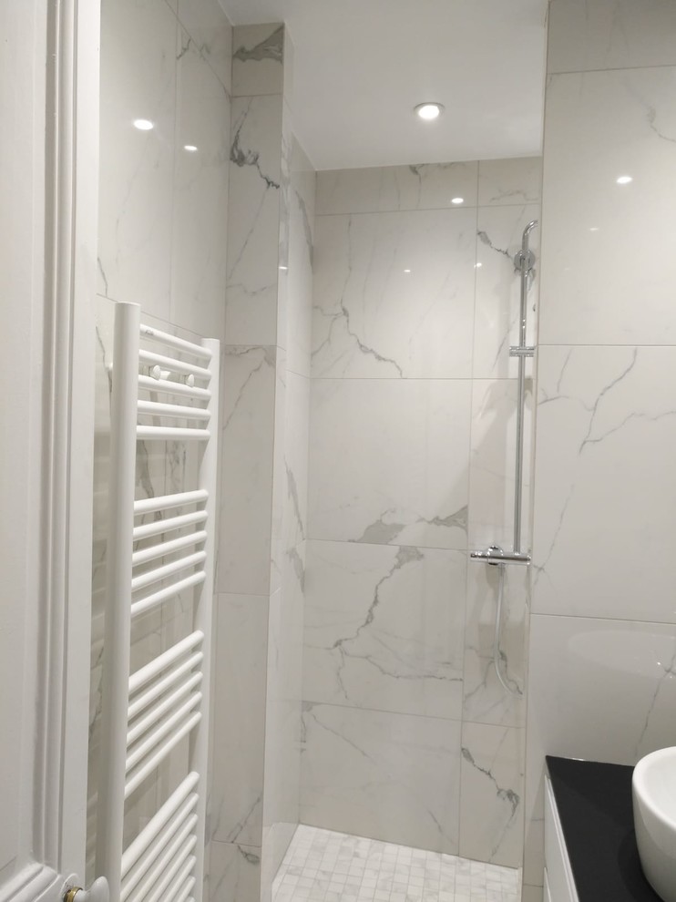 This is an example of a small contemporary 3/4 bathroom in Paris with flat-panel cabinets, white cabinets, a curbless shower, gray tile, ceramic tile, grey walls, ceramic floors, a vessel sink, laminate benchtops, grey floor, an open shower and black benchtops.