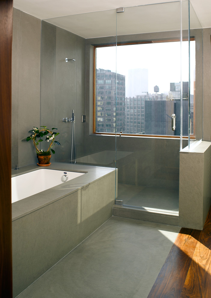 Modern bathroom in New York with an undermount tub, an alcove shower and concrete floors.