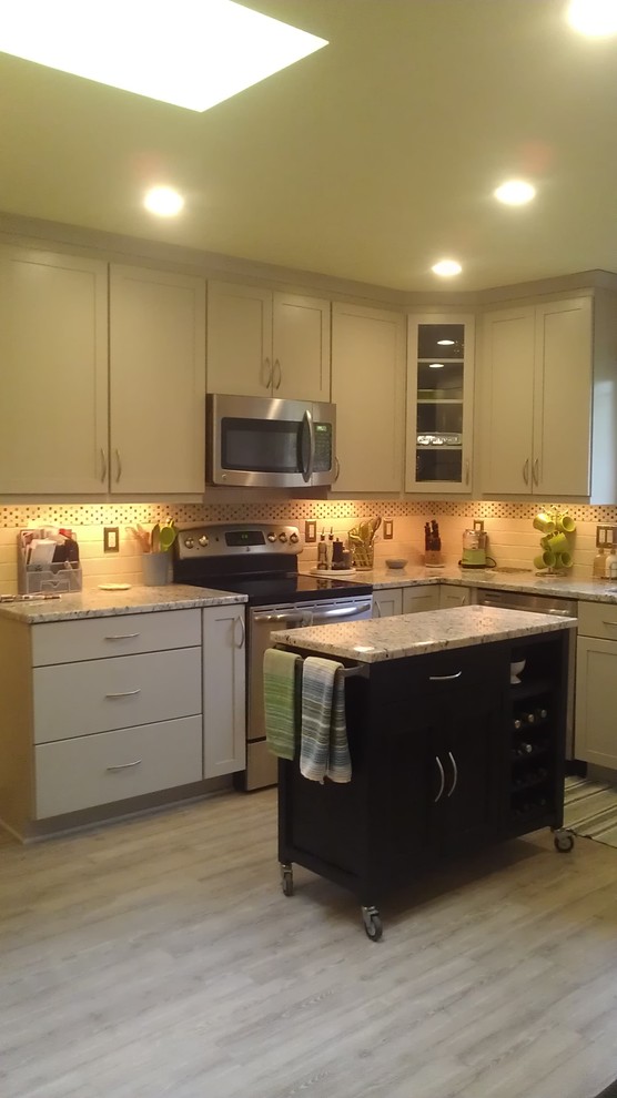 Example of a mid-sized transitional u-shaped vinyl floor eat-in kitchen design with an undermount sink, shaker cabinets, white cabinets, granite countertops, white backsplash, subway tile backsplash, stainless steel appliances and an island
