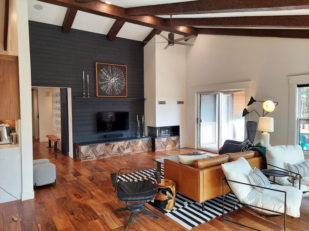 Design ideas for a large contemporary open concept living room in Denver with black walls, dark hardwood floors, a two-sided fireplace, a wall-mounted tv, exposed beam and planked wall panelling.