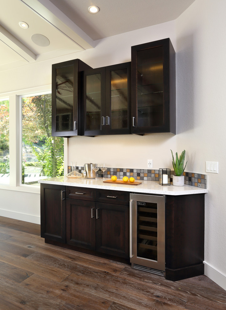 Photo of a small transitional single-wall wet bar in San Francisco with no sink, shaker cabinets, brown cabinets, multi-coloured splashback, mosaic tile splashback and dark hardwood floors.