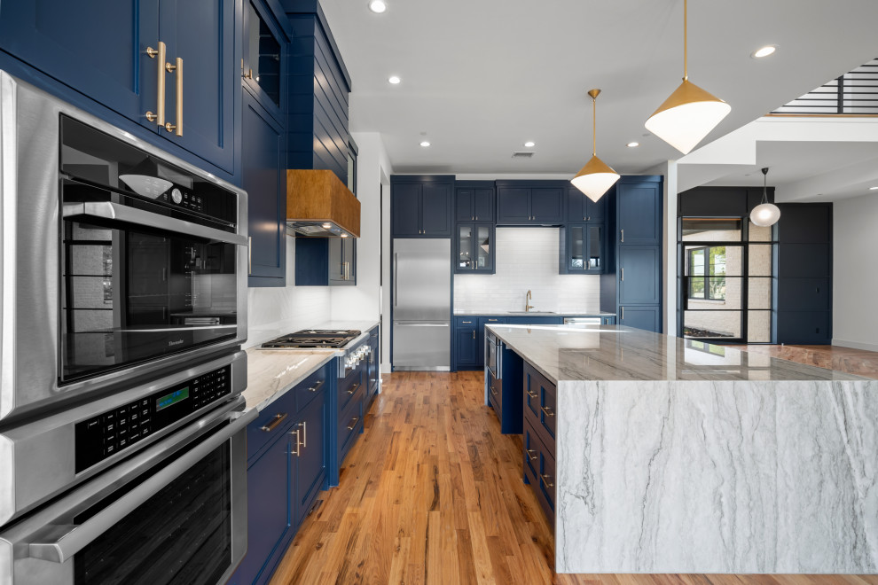 Inspiration for a large modern l-shaped light wood floor and beige floor open concept kitchen remodel in Dallas with an undermount sink, recessed-panel cabinets, blue cabinets, quartzite countertops, white backsplash, subway tile backsplash, stainless steel appliances, an island and gray countertops