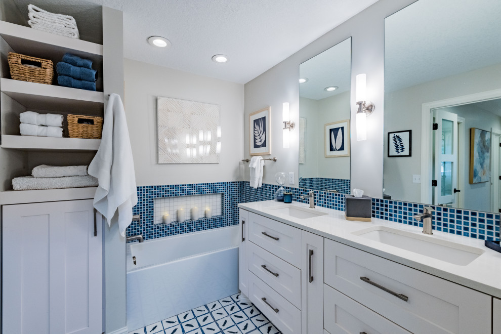 Пример оригинального дизайна: главная ванная комната среднего размера в стиле неоклассика (современная классика) с фасадами в стиле шейкер, белыми фасадами, ванной в нише, душем без бортиков, унитазом-моноблоком, синей плиткой, керамогранитной плиткой, серыми стенами, полом из керамогранита, врезной раковиной, столешницей из кварцита, разноцветным полом, открытым душем, белой столешницей, сиденьем для душа, тумбой под две раковины и встроенной тумбой