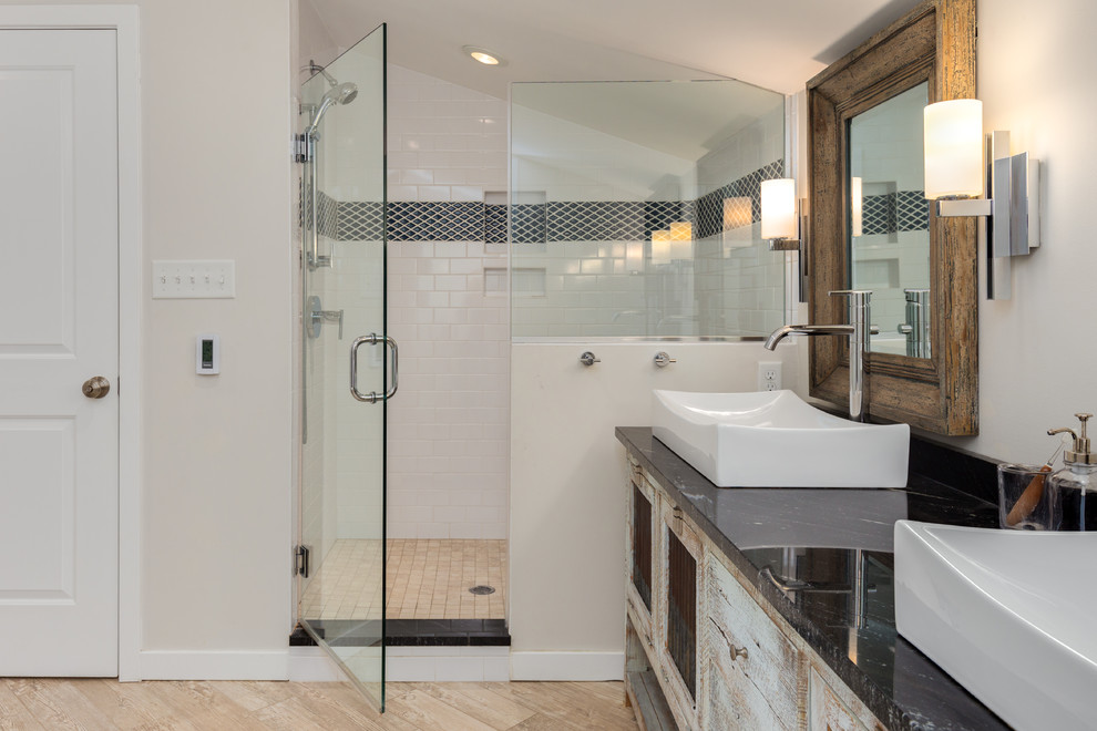 Photo of a mid-sized eclectic master bathroom in DC Metro with furniture-like cabinets, grey cabinets, a freestanding tub, an alcove shower, a two-piece toilet, black and white tile, ceramic tile, grey walls, porcelain floors, a vessel sink, granite benchtops, beige floor, a hinged shower door and black benchtops.