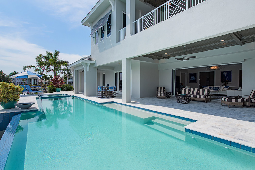 This is an example of a large transitional backyard rectangular infinity pool in Tampa.