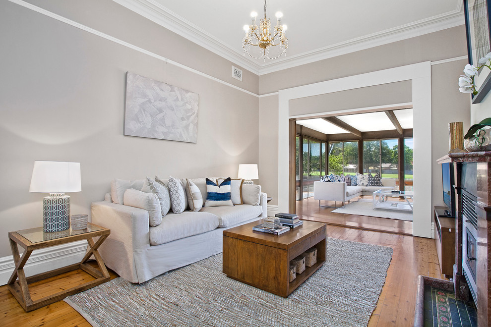 Mid-sized transitional formal open concept living room in Sydney with beige walls, medium hardwood floors, a standard fireplace, a stone fireplace surround and a freestanding tv.