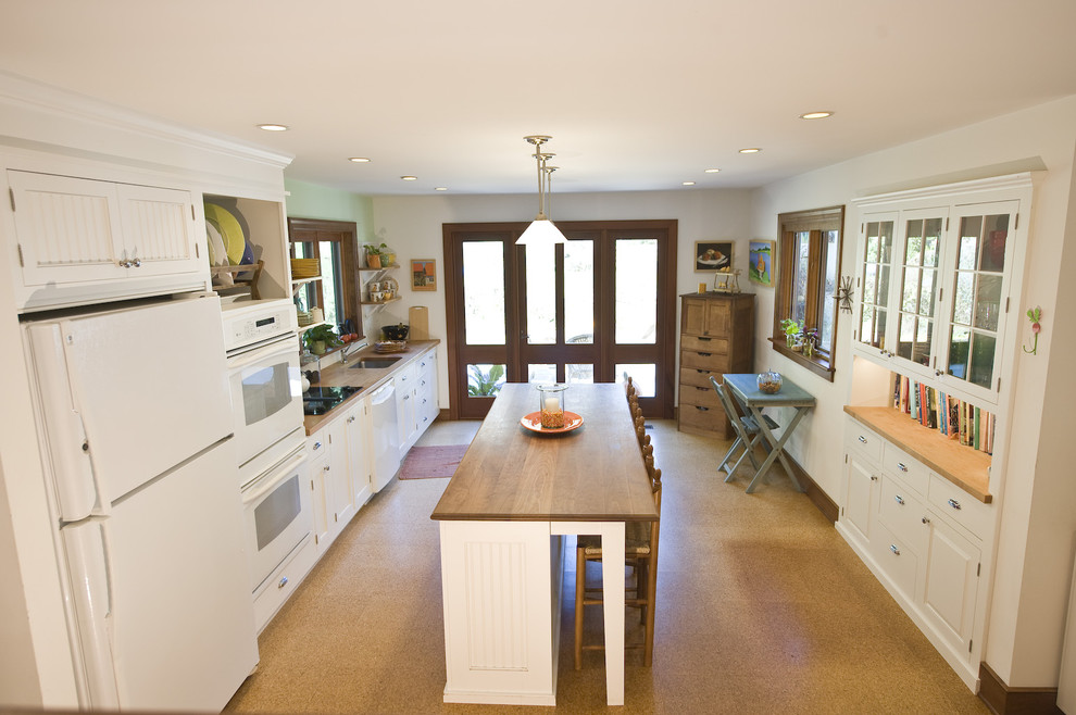 This is an example of a traditional single-wall eat-in kitchen in Philadelphia with white appliances, wood benchtops and white cabinets.