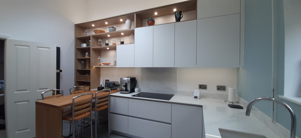 This is an example of a large modern u-shaped eat-in kitchen in Other with an undermount sink, flat-panel cabinets, white cabinets, onyx benchtops, white splashback, black appliances, linoleum floors, with island, grey floor and white benchtop.
