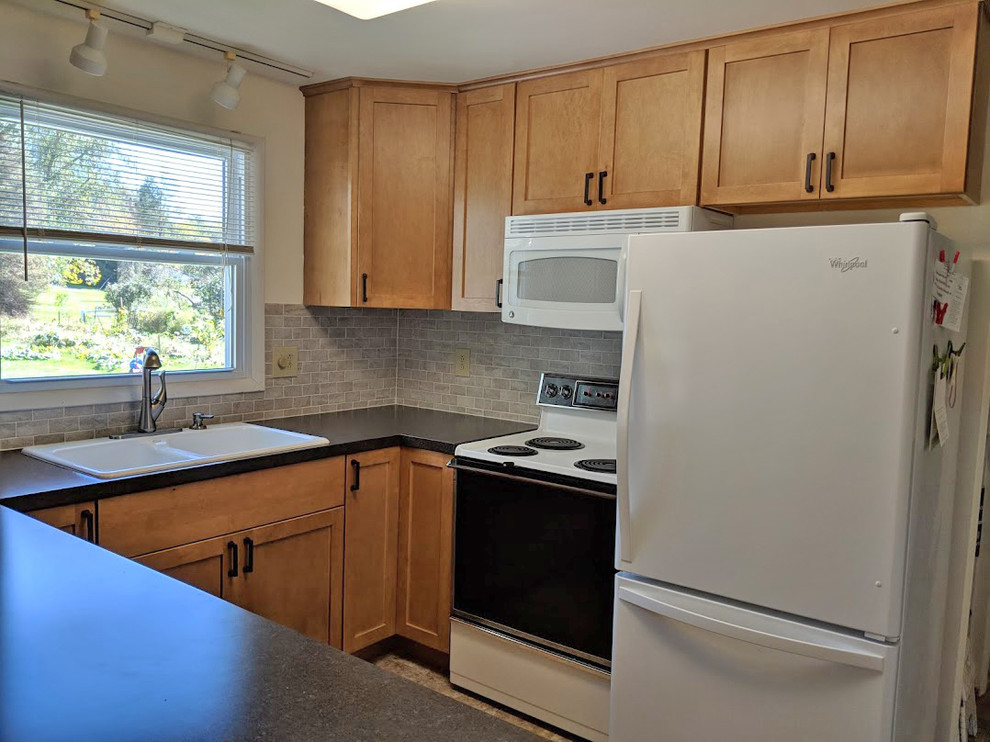 Example of a mid-sized transitional u-shaped linoleum floor and multicolored floor eat-in kitchen design with a double-bowl sink, recessed-panel cabinets, light wood cabinets, laminate countertops, gray backsplash, ceramic backsplash, white appliances, a peninsula and black countertops