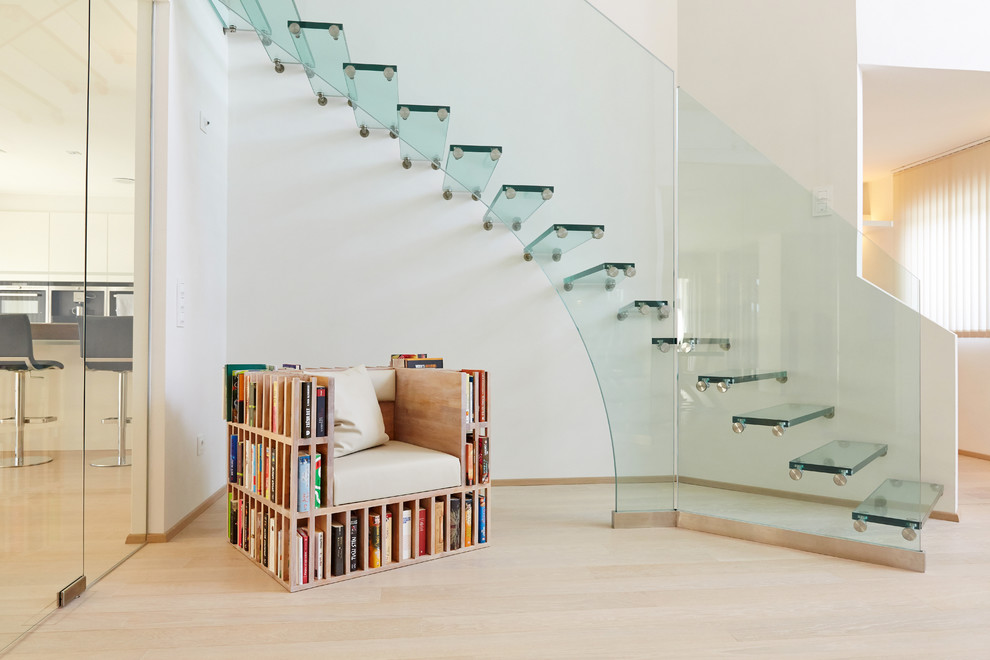 This is an example of a mid-sized midcentury glass curved staircase in Munich with glass railing and open risers.