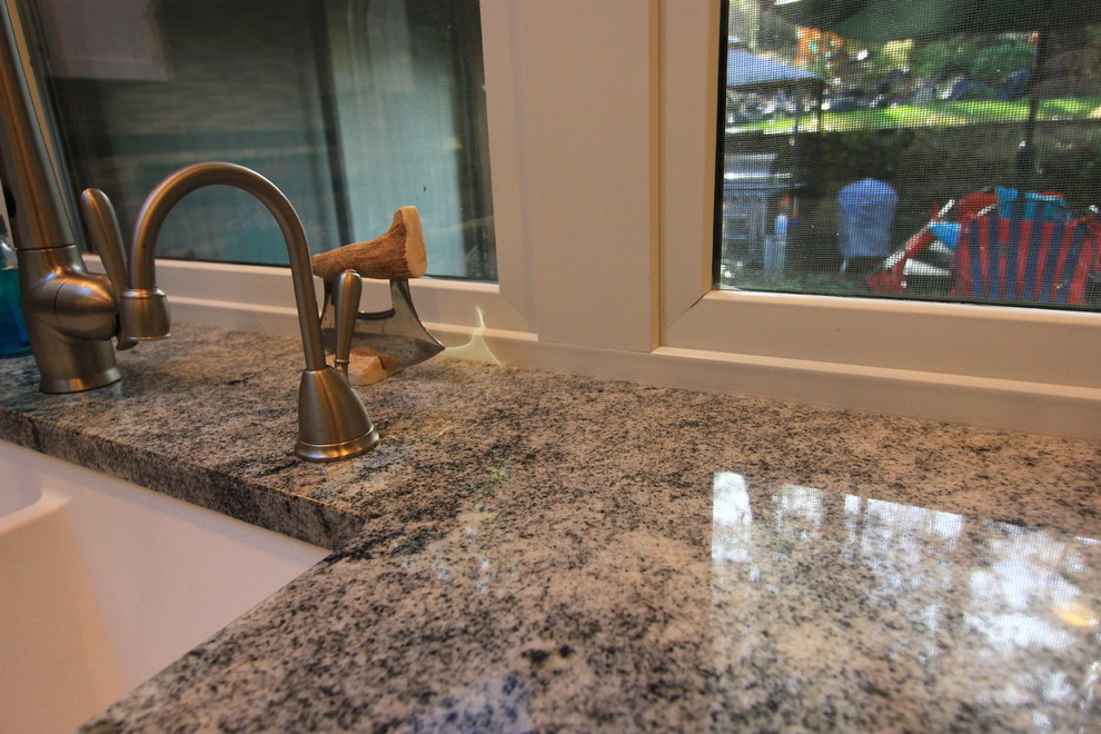 Example of a large transitional u-shaped light wood floor open concept kitchen design with an undermount sink, shaker cabinets, white cabinets, granite countertops, multicolored backsplash, mosaic tile backsplash, stainless steel appliances and an island
