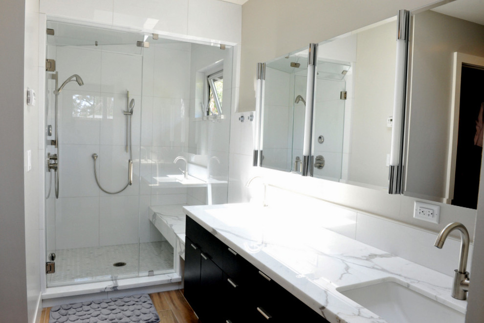 Large contemporary master bathroom in San Francisco with black cabinets, beige walls, flat-panel cabinets, an alcove shower, white tile, porcelain tile, medium hardwood floors, an undermount sink, marble benchtops, brown floor and a hinged shower door.