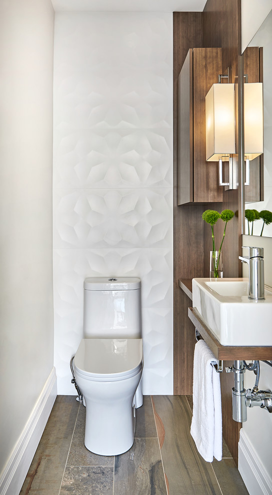 Small contemporary powder room in Raleigh with flat-panel cabinets, medium wood cabinets, a two-piece toilet, white tile, porcelain tile, porcelain floors, wood benchtops, brown benchtops, a wall-mount sink, brown floor and beige walls.