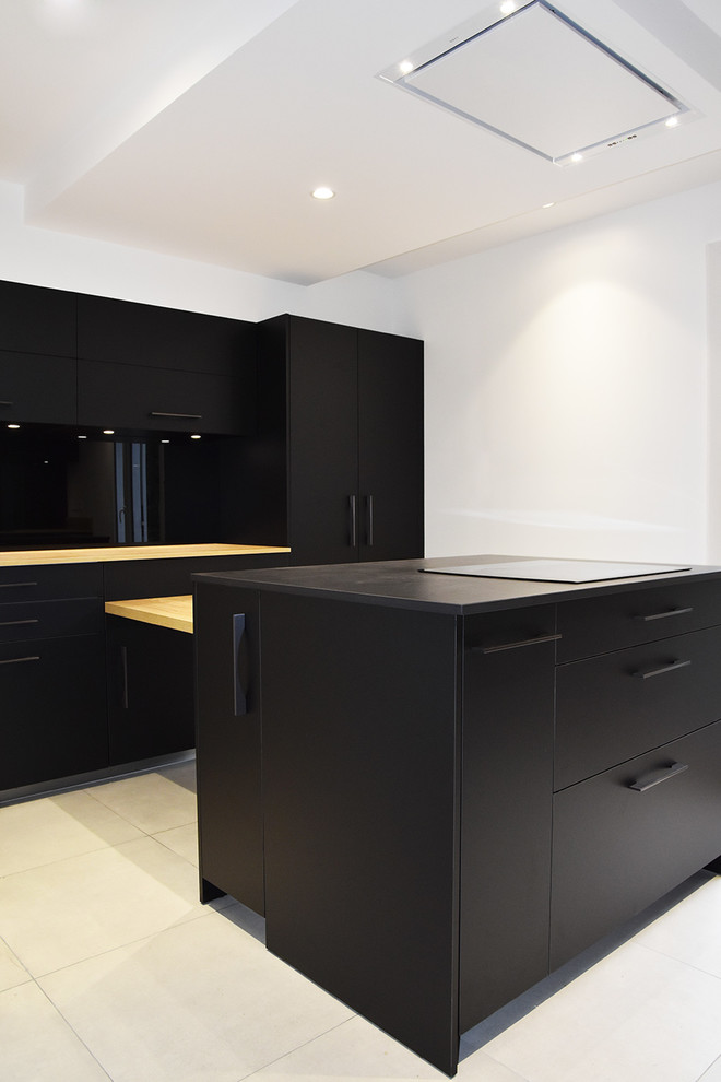 Inspiration for a mid-sized modern galley separate kitchen in Lyon with black appliances, ceramic floors, with island, beige floor, beaded inset cabinets, black cabinets, tile benchtops, black splashback, glass sheet splashback and a double-bowl sink.