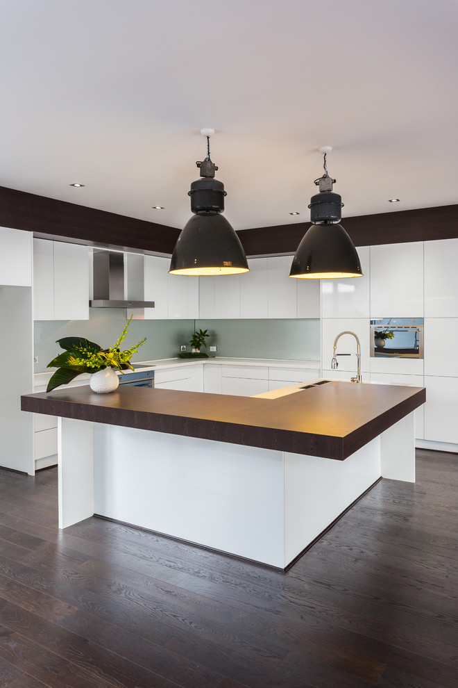Photo of a contemporary eat-in kitchen in Perth with an undermount sink, flat-panel cabinets, white cabinets, solid surface benchtops, grey splashback, glass sheet splashback and stainless steel appliances.