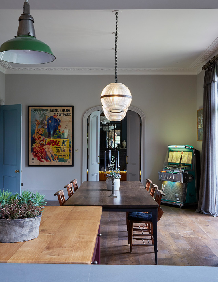 This is an example of an eclectic dining room in London with grey walls, dark hardwood floors and brown floor.