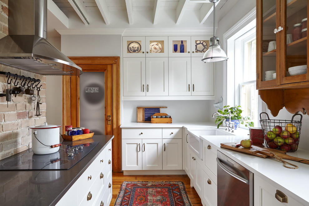 Enclosed kitchen - mid-sized traditional u-shaped medium tone wood floor enclosed kitchen idea in Toronto with a farmhouse sink, white cabinets, stainless steel appliances, shaker cabinets, marble countertops, multicolored backsplash, stone tile backsplash and an island