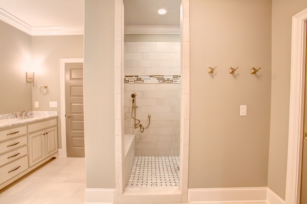 Mid-sized mediterranean wet room bathroom in Other with raised-panel cabinets, light wood cabinets, a drop-in tub, a two-piece toilet, beige tile, pink tile, ceramic tile, beige walls, travertine floors, an undermount sink and marble benchtops.