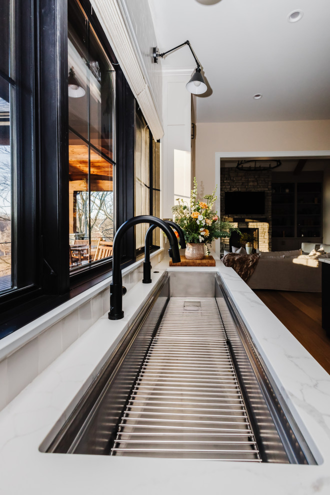 Inspiration for a large rustic u-shaped medium tone wood floor kitchen remodel with an undermount sink, shaker cabinets, beige cabinets, quartzite countertops, white backsplash, ceramic backsplash, paneled appliances and white countertops