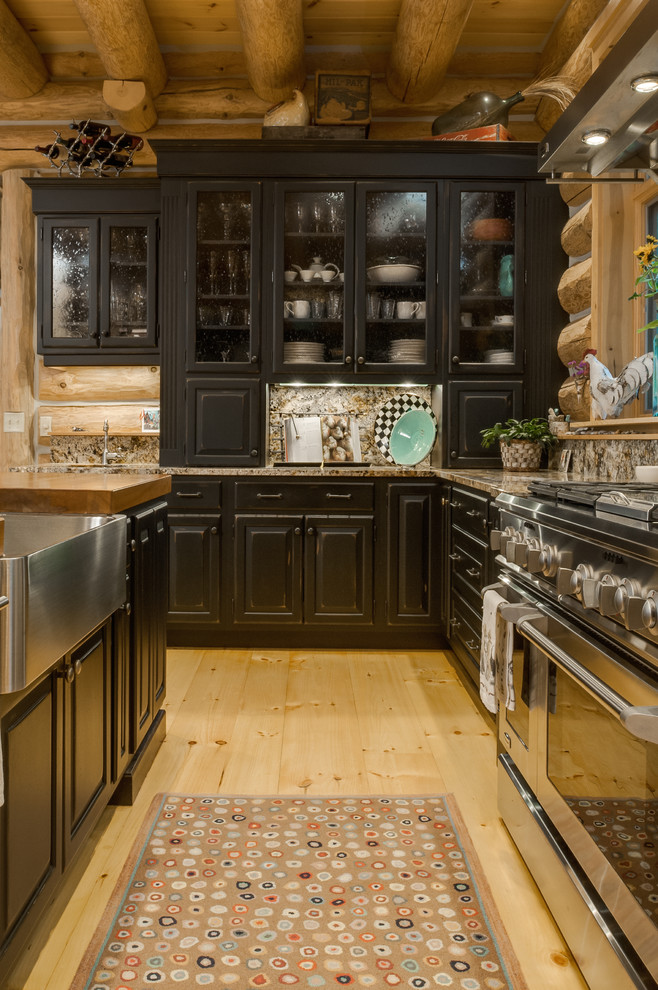 Eat-in kitchen - rustic l-shaped eat-in kitchen idea with an undermount sink, raised-panel cabinets, black cabinets, wood countertops, multicolored backsplash, stone slab backsplash and stainless steel appliances