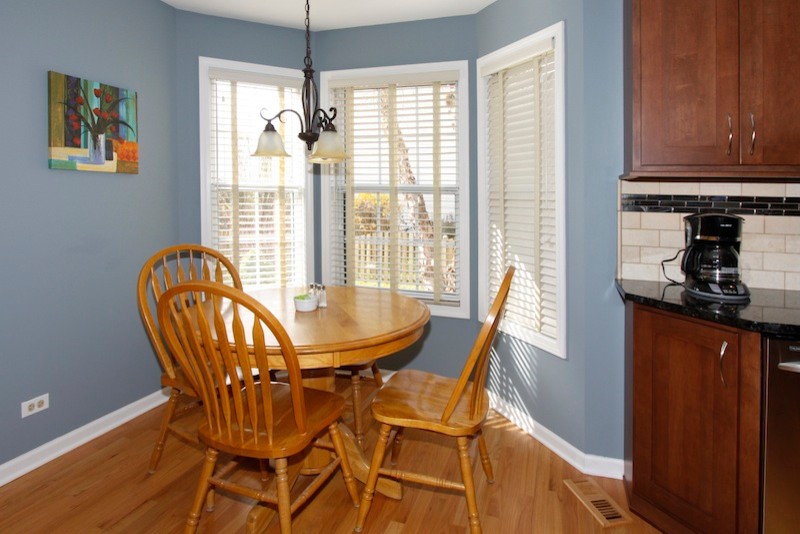 Eat-in kitchen - mid-sized transitional u-shaped light wood floor eat-in kitchen idea in Chicago with an undermount sink, recessed-panel cabinets, medium tone wood cabinets, granite countertops, beige backsplash, stone tile backsplash, stainless steel appliances and no island
