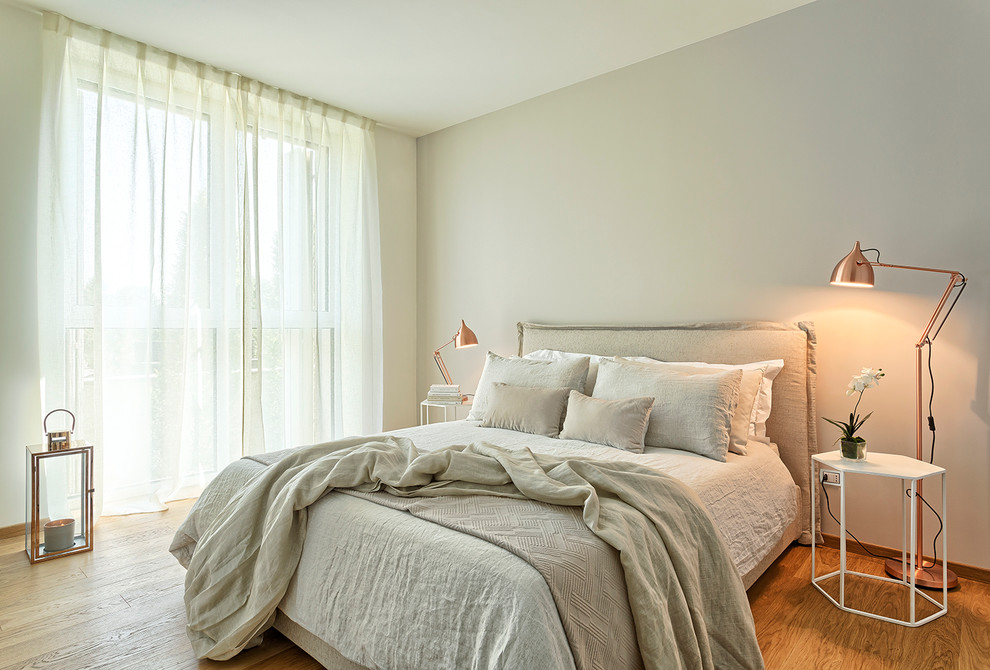 Inspiration for a large scandinavian master bedroom in Bologna with beige walls and medium hardwood floors.