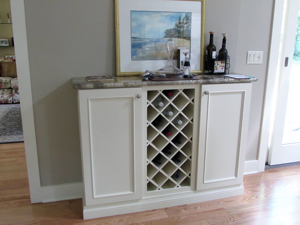 This is an example of a large transitional u-shaped home bar in New York with an undermount sink, recessed-panel cabinets, white cabinets, solid surface benchtops, white splashback, subway tile splashback, light hardwood floors and brown floor.