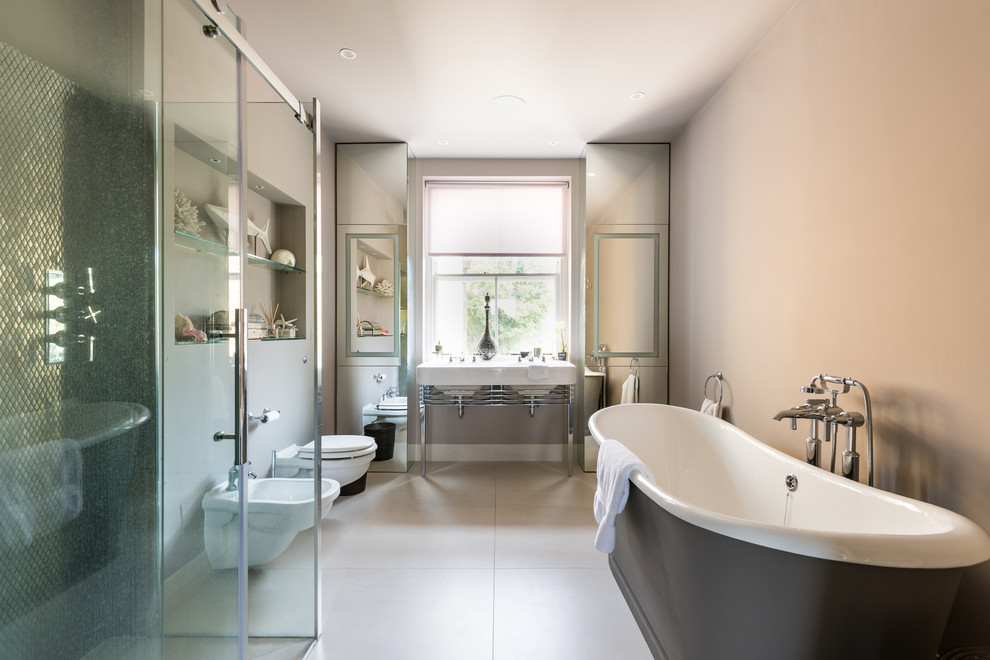 Inspiration for a large transitional wet room bathroom in London with a freestanding tub, a wall-mount toilet, a console sink, grey floor and a sliding shower screen.