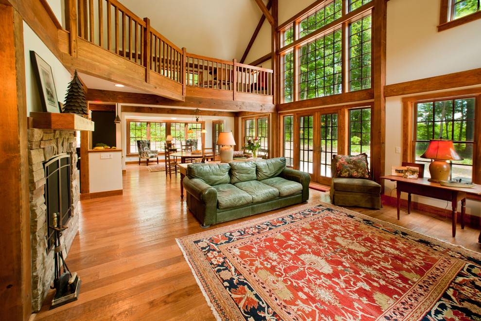 Large traditional loft-style living room in Manchester with white walls, medium hardwood floors, a standard fireplace and a stone fireplace surround.