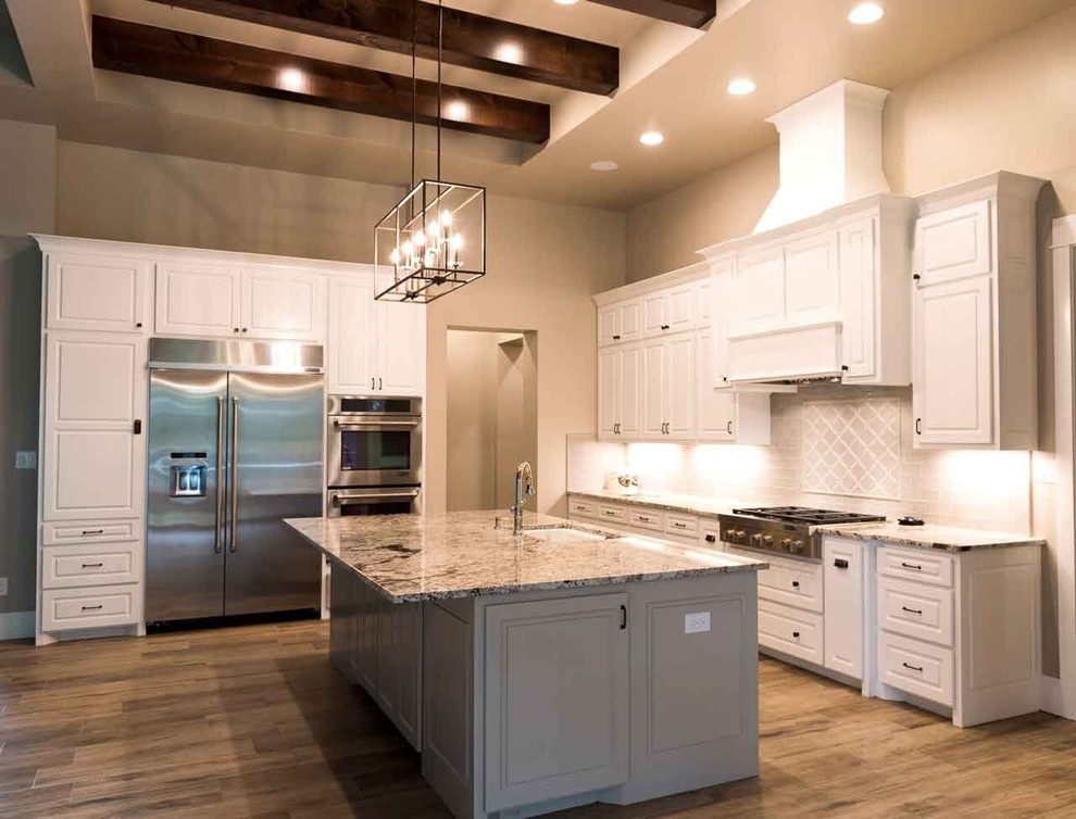 Inspiration for a large transitional l-shaped dark wood floor and brown floor open concept kitchen remodel in Austin with an undermount sink, shaker cabinets, white cabinets, granite countertops, beige backsplash, subway tile backsplash, stainless steel appliances and an island