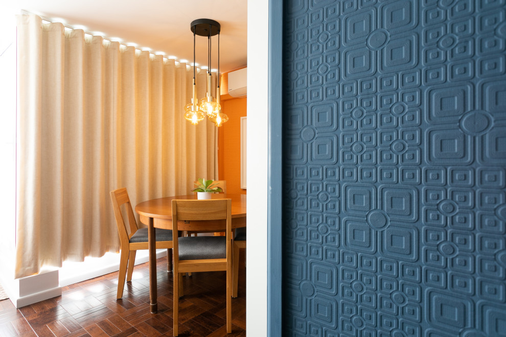 Immagine di una piccola sala da pranzo aperta verso il soggiorno minimalista con pareti arancioni, pavimento in vinile, camino sospeso e carta da parati