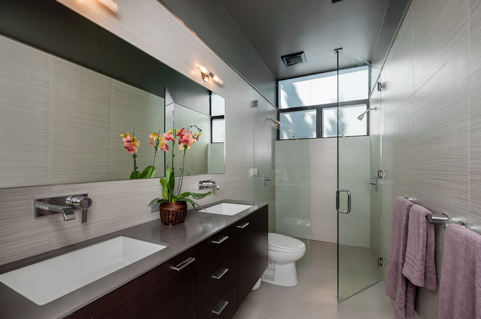 This is an example of a contemporary bathroom in San Francisco with an undermount sink, flat-panel cabinets, dark wood cabinets, an alcove shower and beige tile.