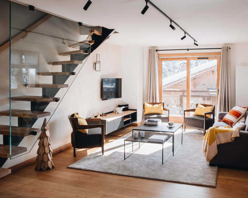 Idée de décoration pour un salon design avec un mur blanc, un sol en bois brun, aucune cheminée, un téléviseur fixé au mur et un sol marron.