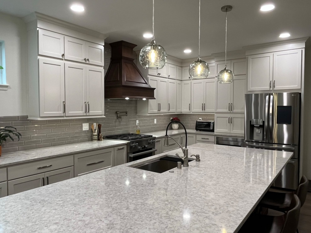 Inspiration for a large transitional l-shaped vinyl floor eat-in kitchen remodel in Seattle with an undermount sink, recessed-panel cabinets, medium tone wood cabinets, quartz countertops, gray backsplash, porcelain backsplash, stainless steel appliances, an island and white countertops
