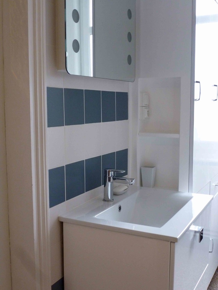 This is an example of a mid-sized scandinavian master bathroom in Lille with a drop-in tub, a shower/bathtub combo, blue tile, ceramic tile, white walls, terrazzo floors and a console sink.