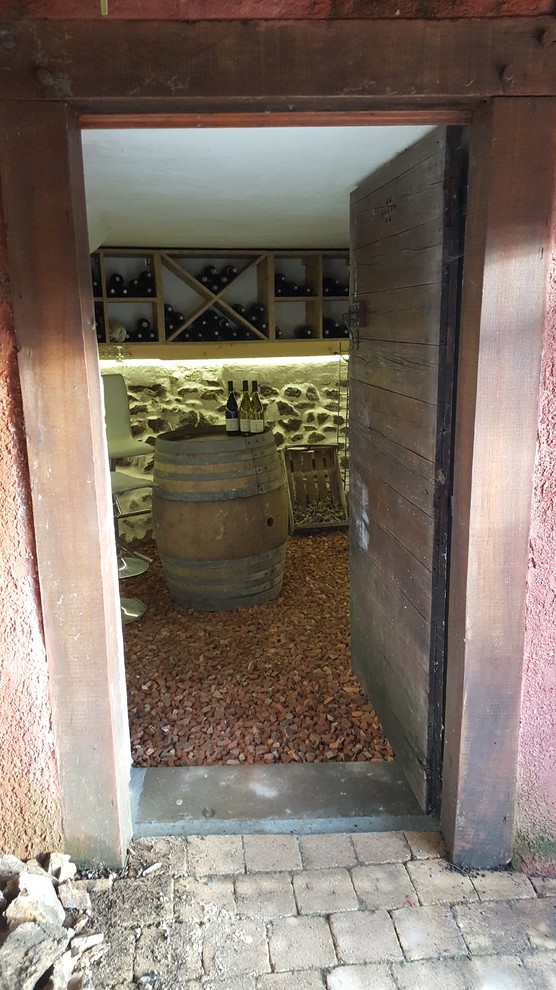 This is an example of a mid-sized country wine cellar in Lyon with terra-cotta floors, diamond bins and red floor.