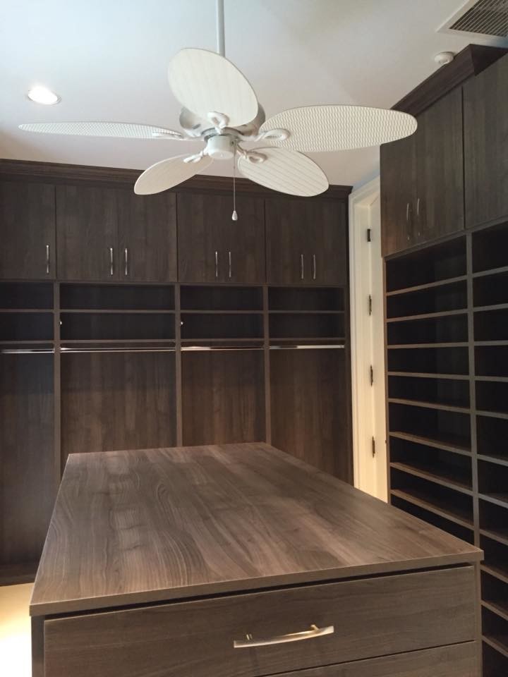 This is an example of a large contemporary gender-neutral walk-in wardrobe in Miami with flat-panel cabinets, dark wood cabinets and beige floor.