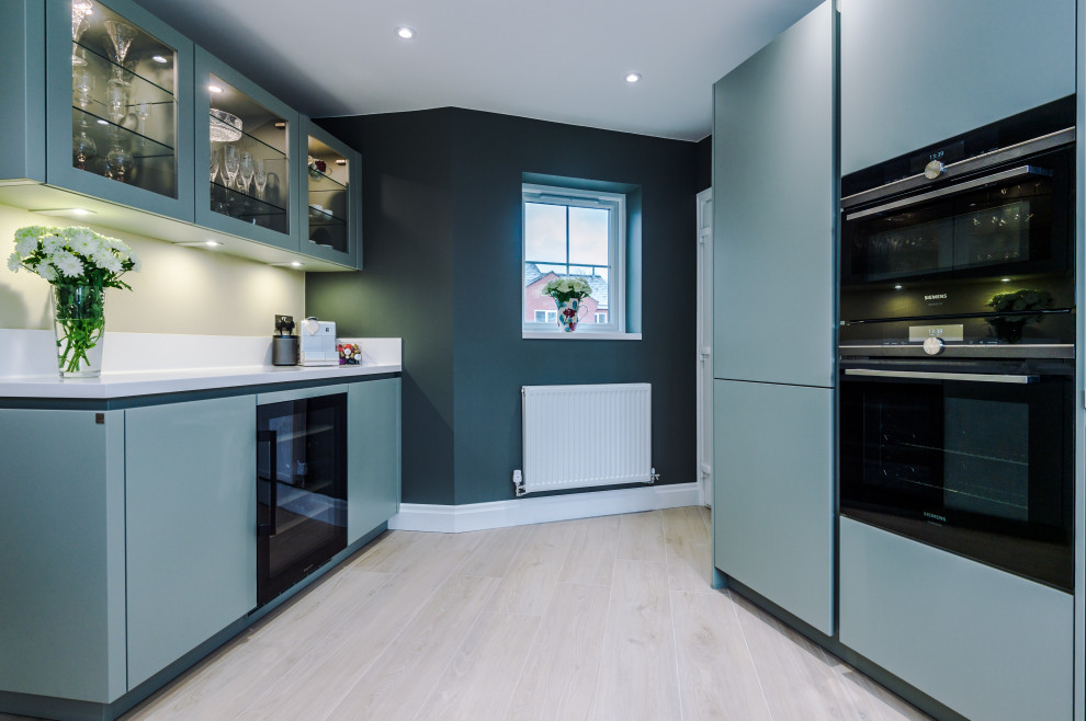 Ejemplo de cocinas en U contemporáneo de tamaño medio con fregadero encastrado, puertas de armario azules y suelo de baldosas de porcelana