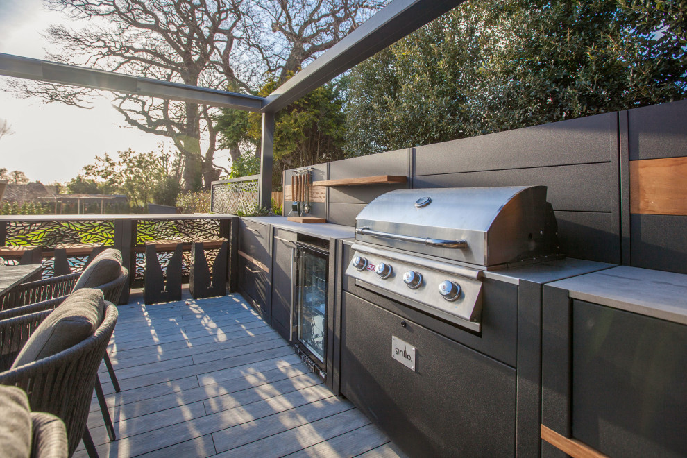 Outdoor kitchen deck - mid-sized contemporary backyard ground level outdoor kitchen deck idea in Surrey with a pergola