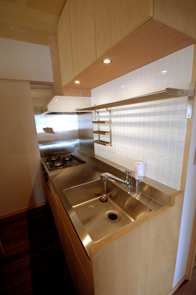 This is an example of a small galley open plan kitchen in Tokyo with an integrated sink, open cabinets, brown cabinets, stainless steel worktops, metallic splashback, black appliances, dark hardwood flooring, brown floors and brown worktops.