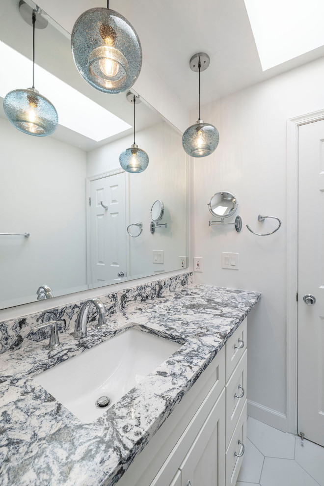 На фото: ванная комната среднего размера в стиле неоклассика (современная классика) с фасадами в стиле шейкер, белыми фасадами, ванной в нише, душем над ванной, белой плиткой, керамогранитной плиткой, полом из керамогранита, врезной раковиной, столешницей из искусственного кварца, белым полом, душем с раздвижными дверями, разноцветной столешницей, тумбой под одну раковину и встроенной тумбой