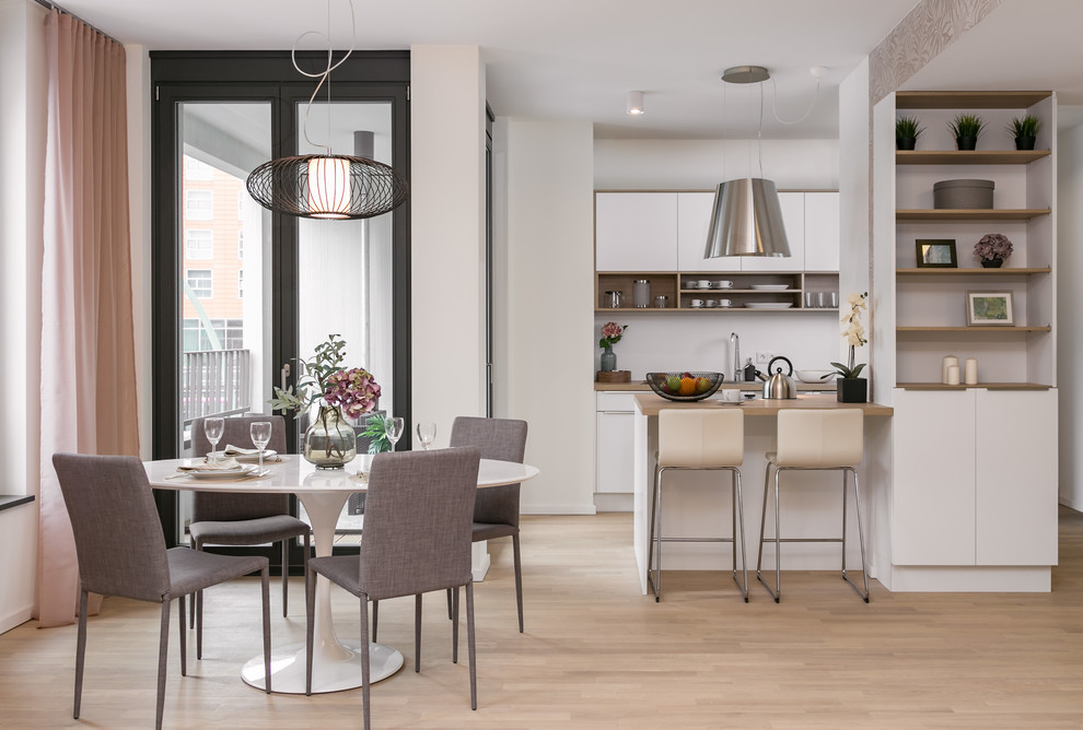 Photo of a mid-sized contemporary galley eat-in kitchen in Berlin with a peninsula, flat-panel cabinets, white cabinets, wood benchtops, white splashback, light hardwood floors, beige floor and brown benchtop.