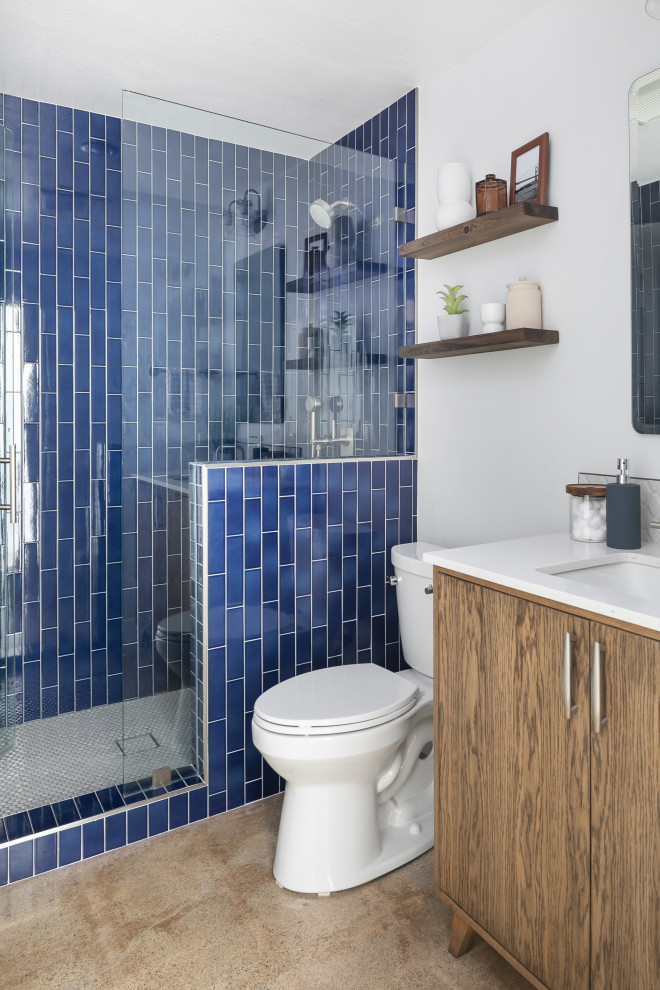 Exempel på ett mellanstort 50 tals vit vitt badrum med dusch, med möbel-liknande, skåp i mellenmörkt trä, en toalettstol med separat cisternkåpa, blå kakel, keramikplattor, vita väggar, betonggolv, ett undermonterad handfat, bänkskiva i kvarts, grått golv och dusch med gångjärnsdörr