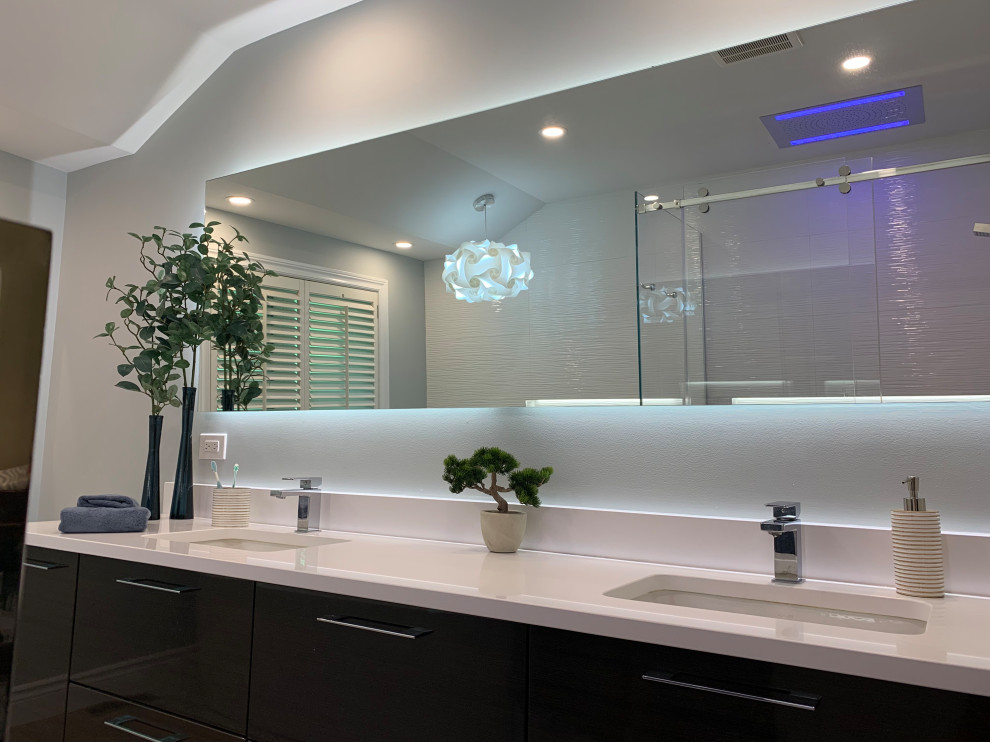 Photo of a large contemporary master bathroom in Montreal with flat-panel cabinets, brown cabinets, a freestanding tub, a curbless shower, a one-piece toilet, white tile, porcelain tile, grey walls, porcelain floors, an undermount sink, engineered quartz benchtops, grey floor, a sliding shower screen, white benchtops, a niche, a double vanity and a floating vanity.