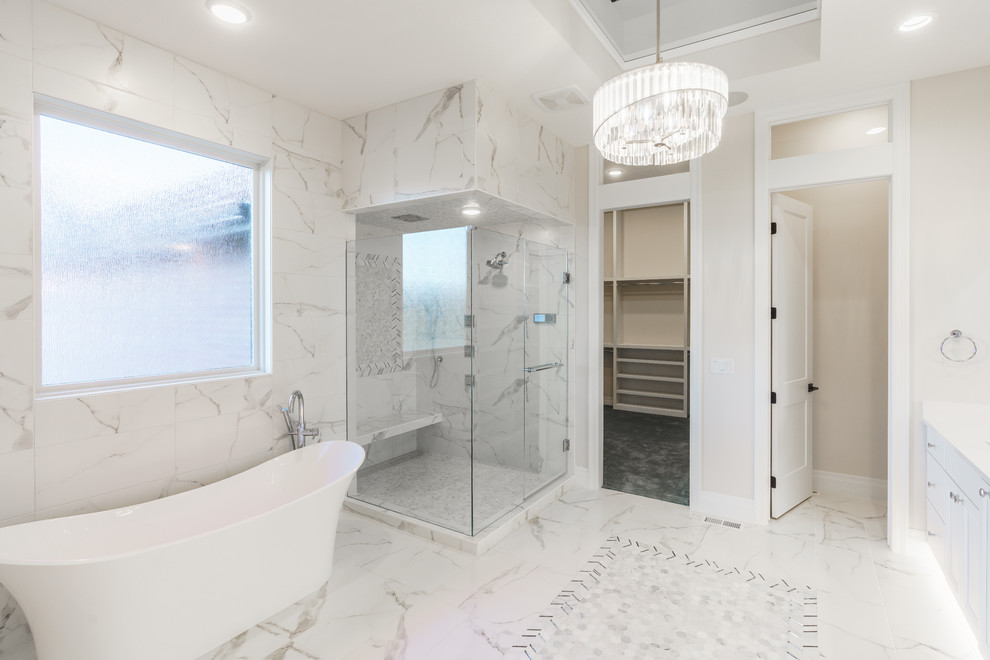 This is an example of a large transitional master bathroom in Wichita with flat-panel cabinets, white cabinets, a freestanding tub, gray tile, marble, white walls, marble floors, a vessel sink, engineered quartz benchtops, white floor, a hinged shower door, white benchtops, a corner shower, an enclosed toilet, a double vanity and a built-in vanity.