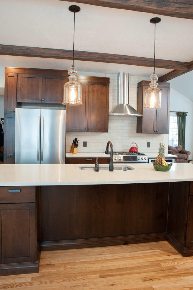 Photo of a large transitional galley eat-in kitchen in Denver with a single-bowl sink, shaker cabinets, medium wood cabinets, quartz benchtops, beige splashback, porcelain splashback, stainless steel appliances, light hardwood floors, with island, yellow floor and white benchtop.