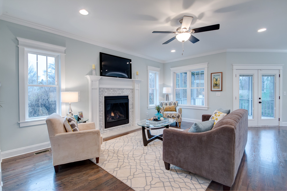 Photo of an arts and crafts open concept living room in Raleigh with grey walls, dark hardwood floors, a standard fireplace, a stone fireplace surround and a wall-mounted tv.